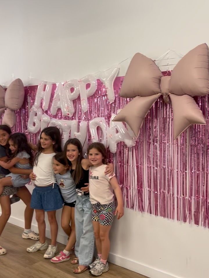 Girls posing at a pink bow backdrop