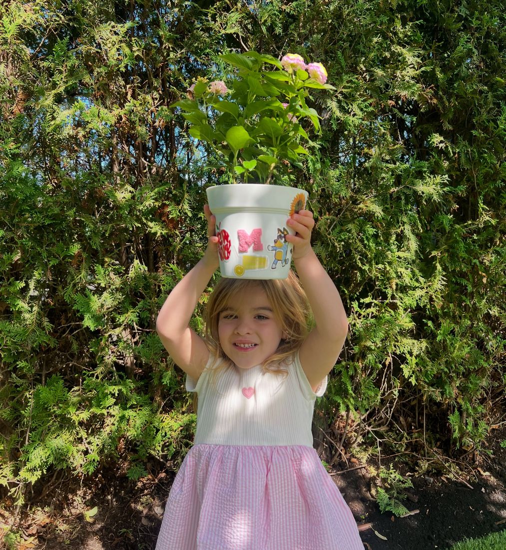 A birthday girl holding up the flower pot she planted